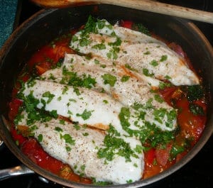 A pan of vegetable and chorizo sauce with seabass