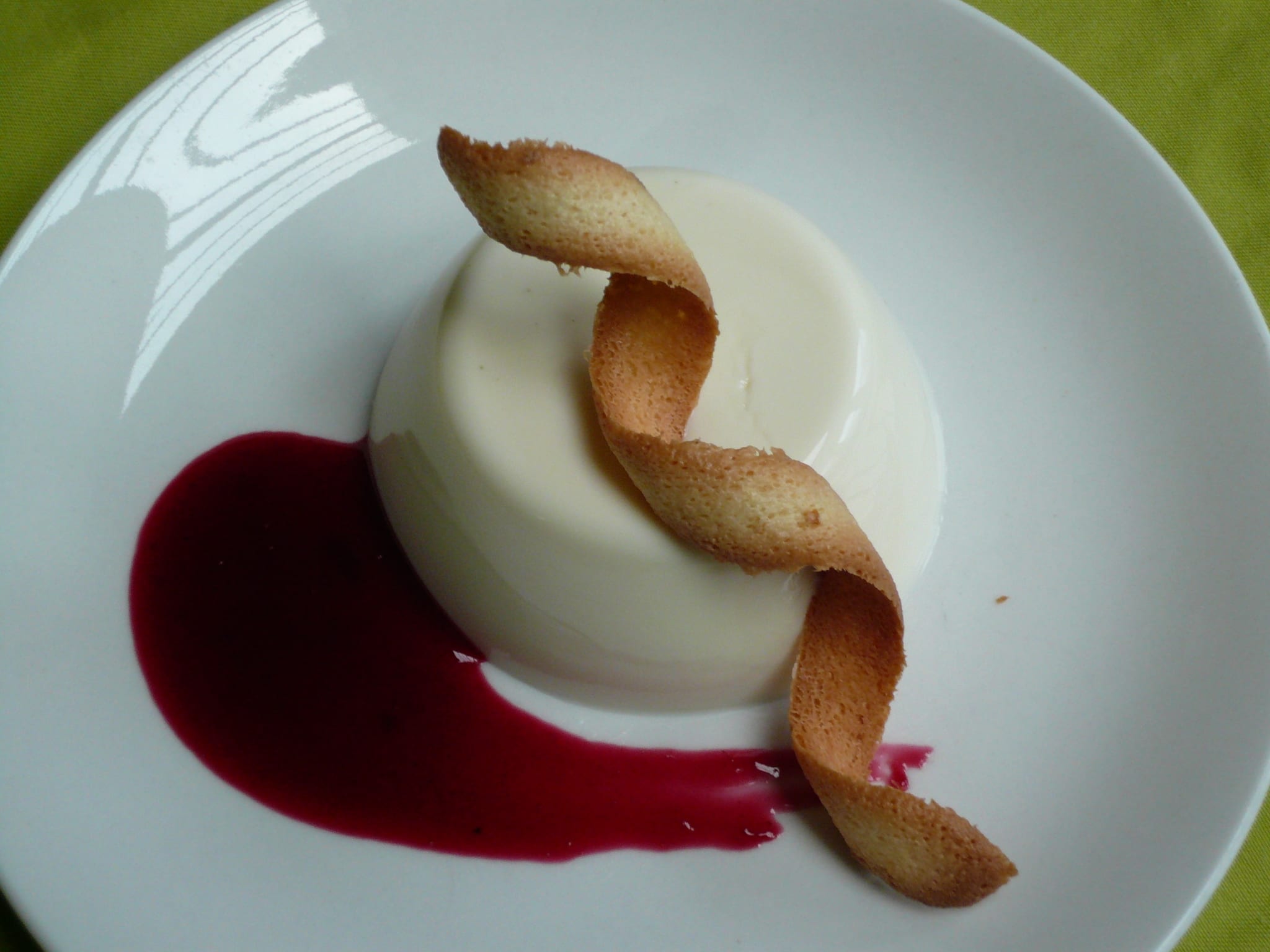 An image of vanilla cream with black currant coulis and tuille twils