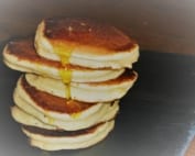 A stack of scotch pancakes with syrup trickling down them