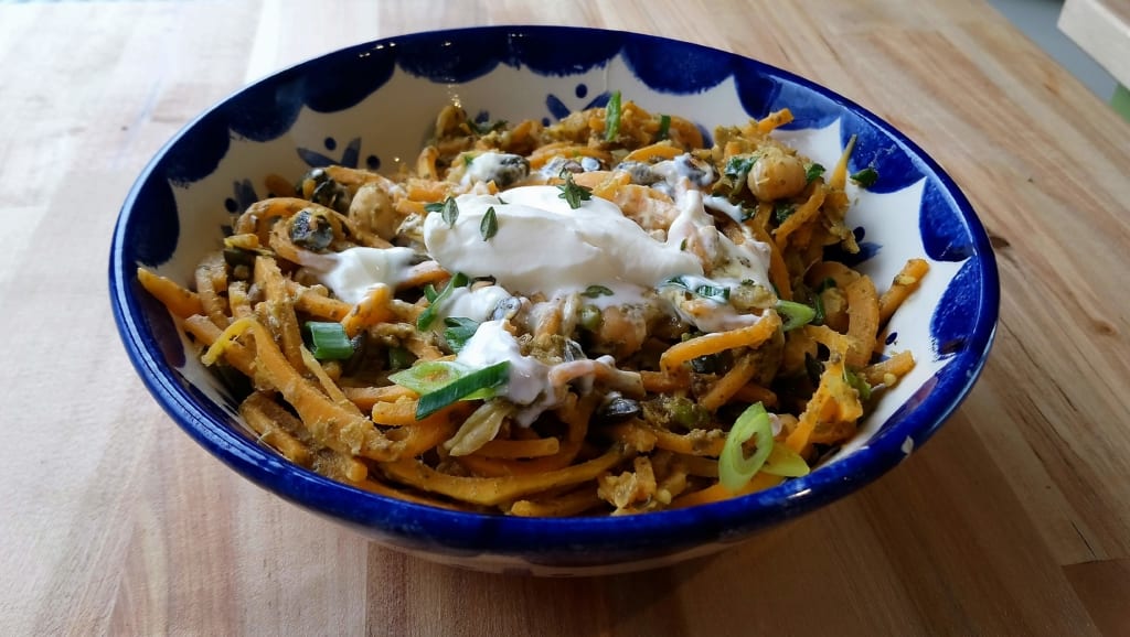 A bowl of spiralised butternut squash with crushed chick peas and pesto sauce