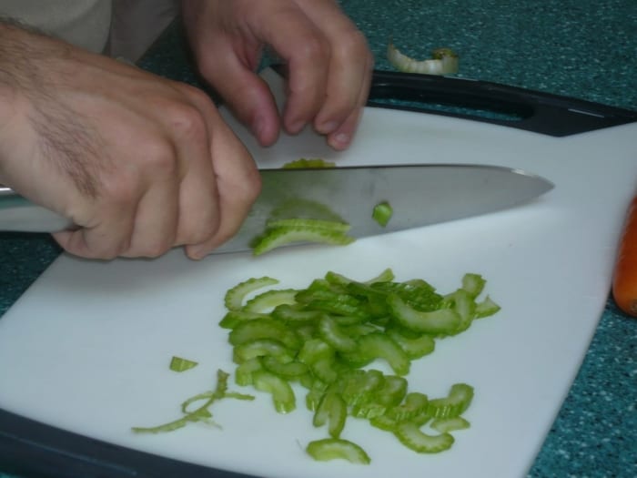 Picture of someone holding a knife the correct way and chopping celery