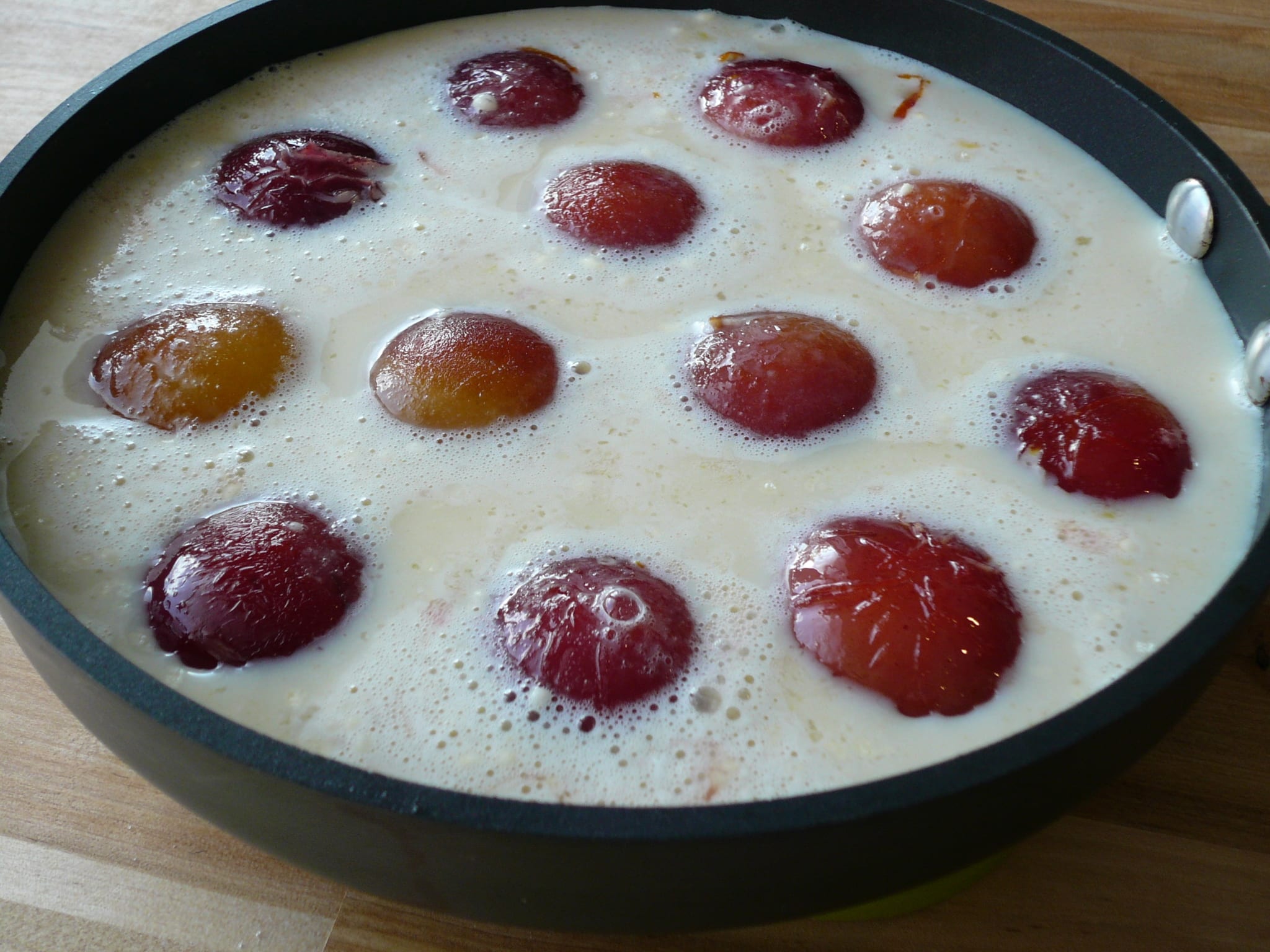 Roasted halved plums in batter ready for the oven