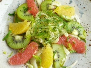 thinly sliced fennel tossed with sliced kiwi fruit, mint & citrus juice. decorated with pink grapefruit, orange & kiwi fruit slices.