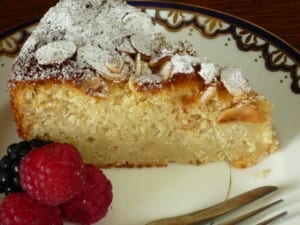 A slice of apple, almond and cinnamon cake with a garnish of rasperries