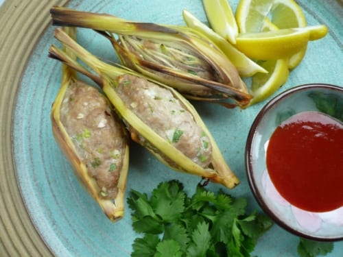 Pork meatballs encased in lemongrass stalks served with chilli sauce, coriander and lemon