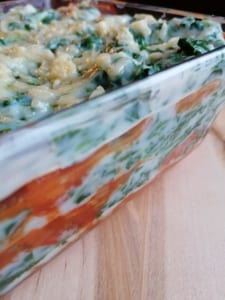 A glass dish showing layers of tomato & spinach lasagne