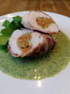 A dish of chicken breast stuffed with vegetables and served with a watercress sauce