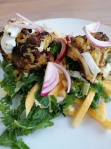 An image of roasted chermoula cauliflower wedges with kale and green mango salad