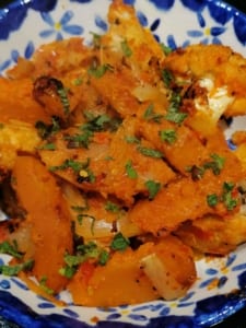 A dish of roasted vegetables with red pepper sauce
