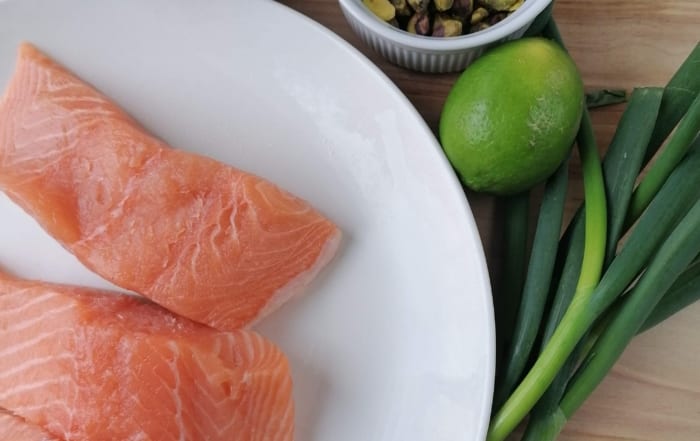 An image of salmon fillets, spring onions, pistachio nuts, couscous & lime