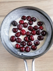 A flour dusted frying pan with batter and cherries
