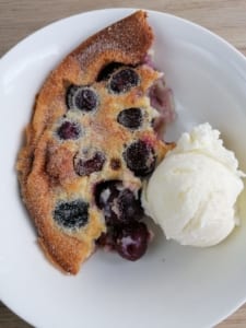 A portion of black cherry clafoutis served with ice cream