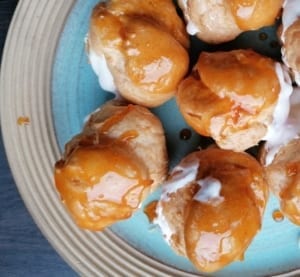 An image of a platter of caramel choux puffs filled with raspberry maple cream filling